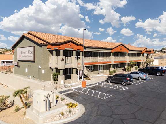 A building with the sign "Desert Mesa" is surrounded by a parking lot.