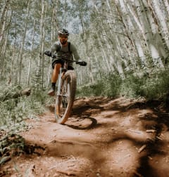 a man riding a bike down a dirt trail in the woods