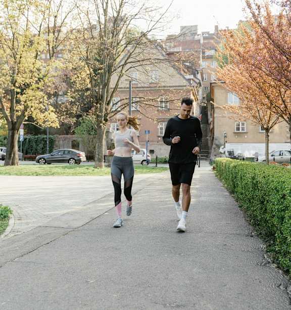 Two people jogging on a path in a park.