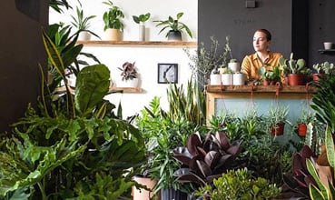 a woman standing in a room full of plants