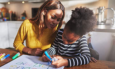 a woman helping a child write on a piece of paper