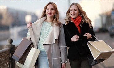 two women walking down the street holding shopping bags