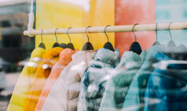 A row of coats in various colors hang on a rack.