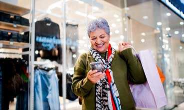 A woman is shopping and holding a phone in her hand.