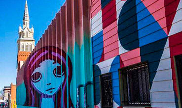 A mural of a woman's face is painted on a building. at Waterford RiNo Apartments, Colorado