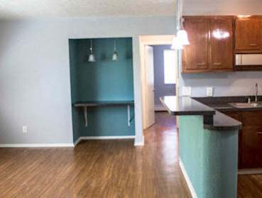 A kitchen with a blue wall and wooden floors.