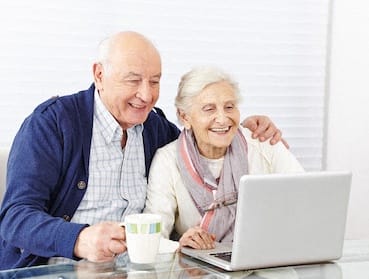 elderly couple looking at laptop computer together