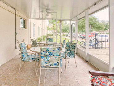 patio with chairs, tables, and fans at Holy Cross Manor I in Palmetto, FL