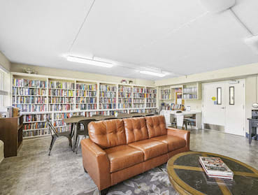large library with comfortable couches, reading table with chairs, and wall full of books