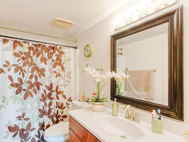bathroom with large vanity, mirror, over mirror lighting, and bathroom decor