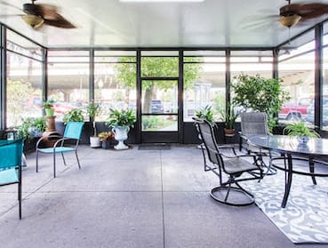 screened in patio with chairs, tables, ceiling fans, and plants