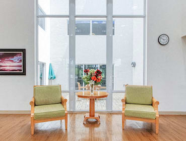Two chairs and a table in front of a window in lobby