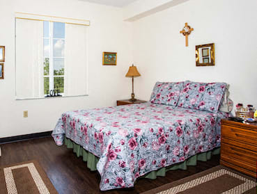 bedroom with hardwood-style flooring, large window, and model furnishings