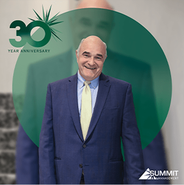 a man in a suit and tie standing in front of a 30th anniversary logo
