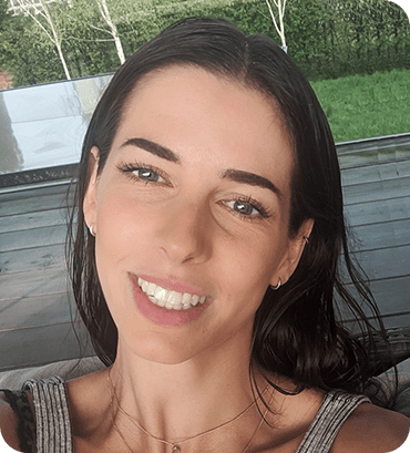 a woman smiling with her eyes closed and a bench in the background