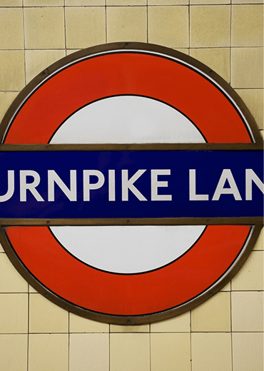 A round sign with a blue band and the words "Burnpike Lane" written on it.
