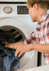 a man is putting clothes into a washing machine