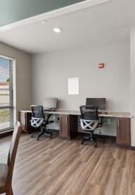 an office with two desks and chairs and a window
