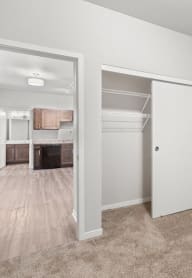 an open doorway into a living room with a closet and a kitchen