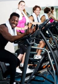 a diverse group of people working out in on eliptical machines in a fitness center