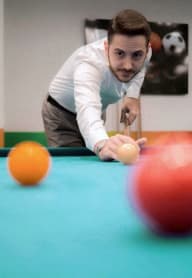 a man is cueing an orange ball on a pool table