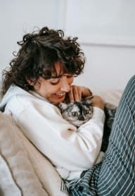 a woman laying on a couch holding a cat