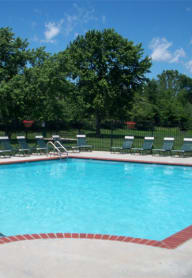 a large swimming pool with chaise lounge chairs and trees in the background