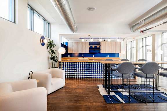 A modern living room with a white sofa, a wooden table, and a blue and white tiled backsplash.