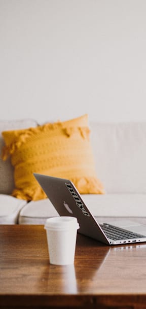 A laptop is open on a table with a cup of coffee in front of it.at Tigardville Apartments, Tigard, OR