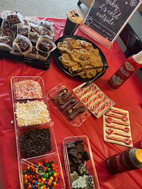 A table with a red tablecloth is filled with various snacks and a sign that says "Daddy is cold outside".