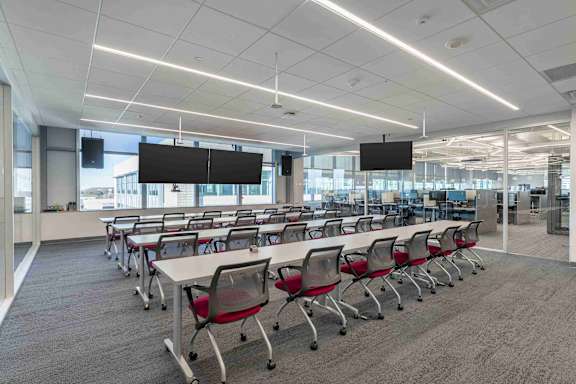 A conference room with white tables and red chairs.