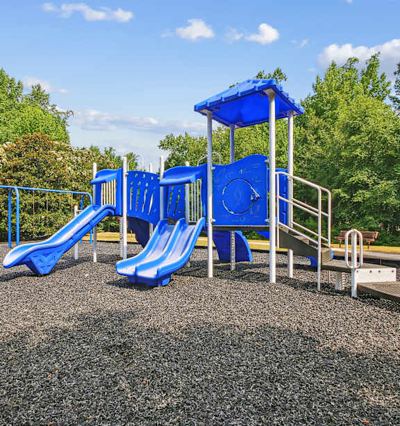 A playground with a blue slide and a blue canopy.