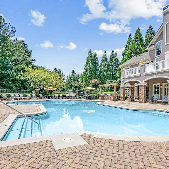 A swimming pool surrounded by a brick border and a metal fence.