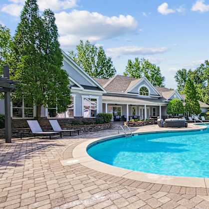 A large swimming pool in a backyard with a house in the background.