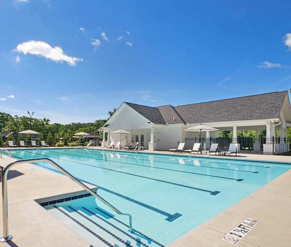 a swimming pool with chairs and a building in the background