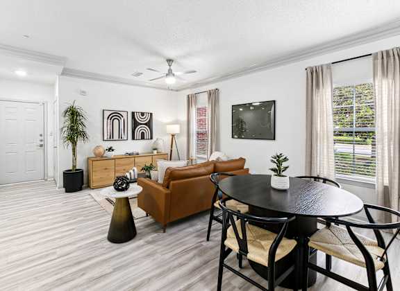 A living room with a brown couch, a black table, and a ceiling fan.