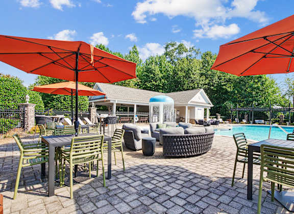 A patio with tables and chairs and umbrellas.