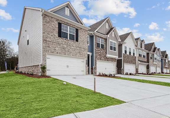 a row of houses with white garage doors and a green lawn