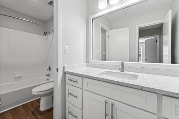 A white bathroom with a toilet, sink, and mirror.