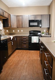 A kitchen with wooden floors and black appliances.