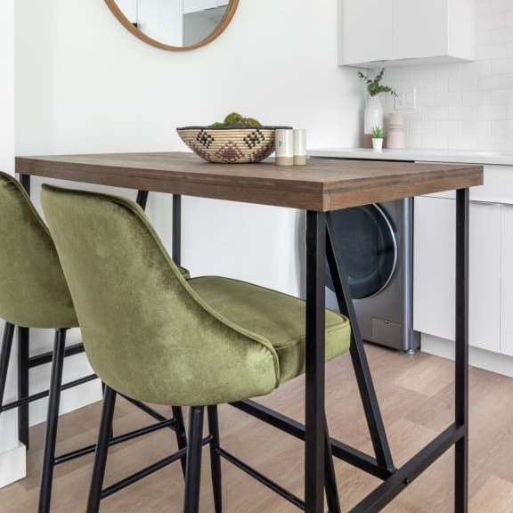 a small kitchen table with two green chairs and a round mirror above it