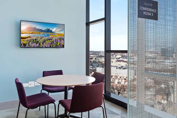 A conference room with a table and chairs and a view of the city.