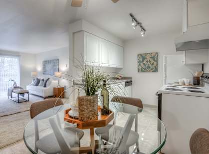 A modern living room with a glass dining table and chairs.