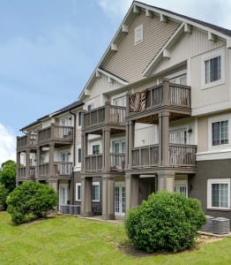 a building with multiple balconies and a pond in front of it