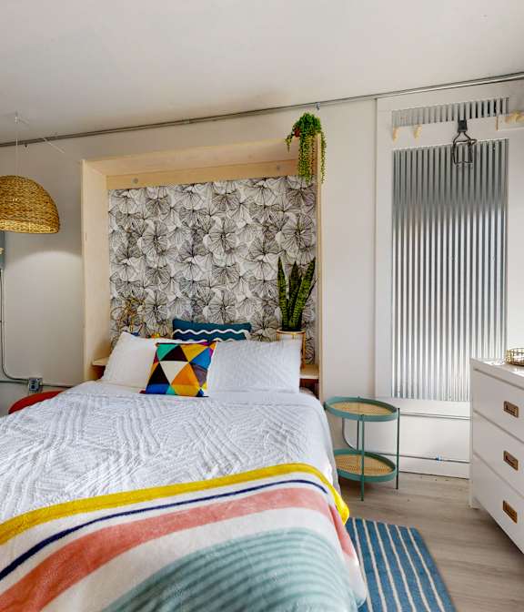 A bedroom with a bed, desk, and chair.
