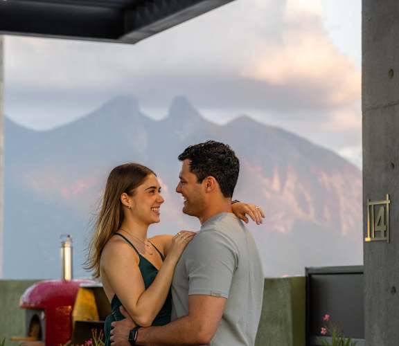 a man and woman hugging with mountains in the background