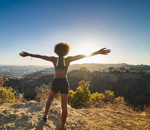 a woman standing on a hill with her arms outstretched