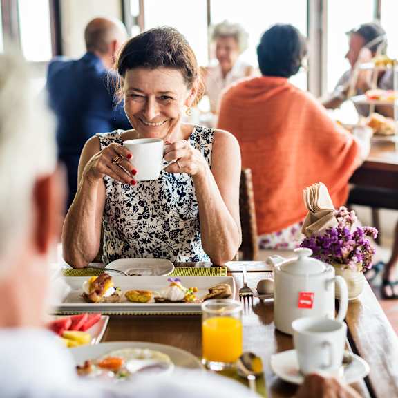 A woman is sitting at a table with a plate of food in front of her.