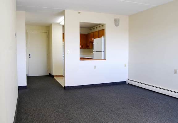 A white room with a kitchen in the background.