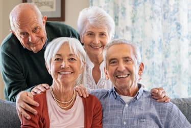 A group of four elderly people sitting on a couch.